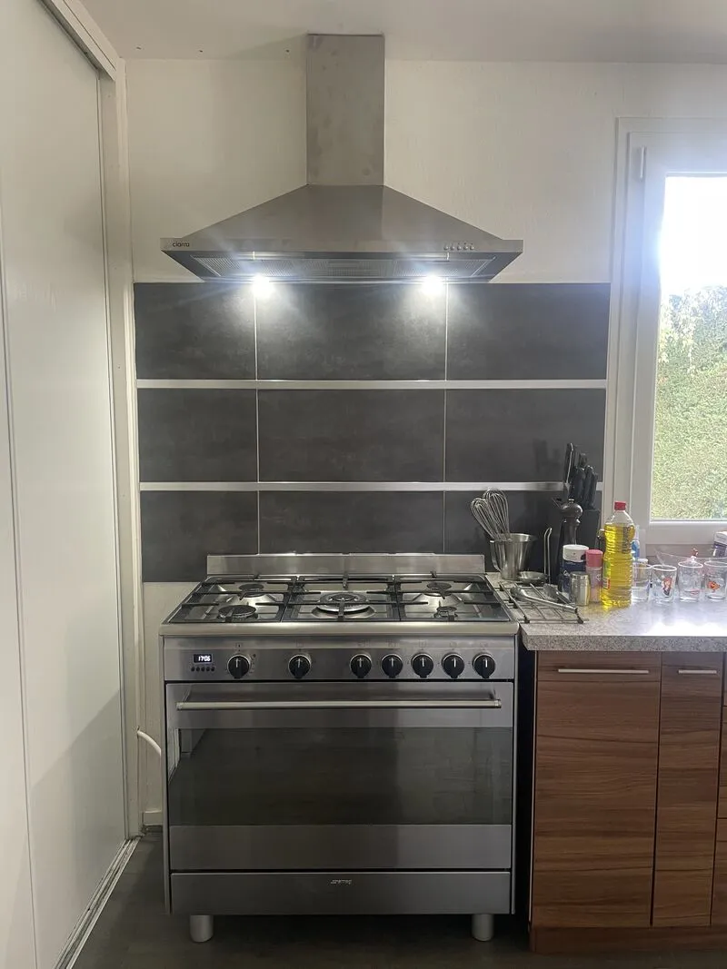 Hotte inox allumée au-dessus de la cuisinière